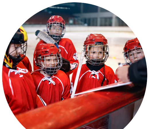 A kids in hockey gear listening to coach off-frame